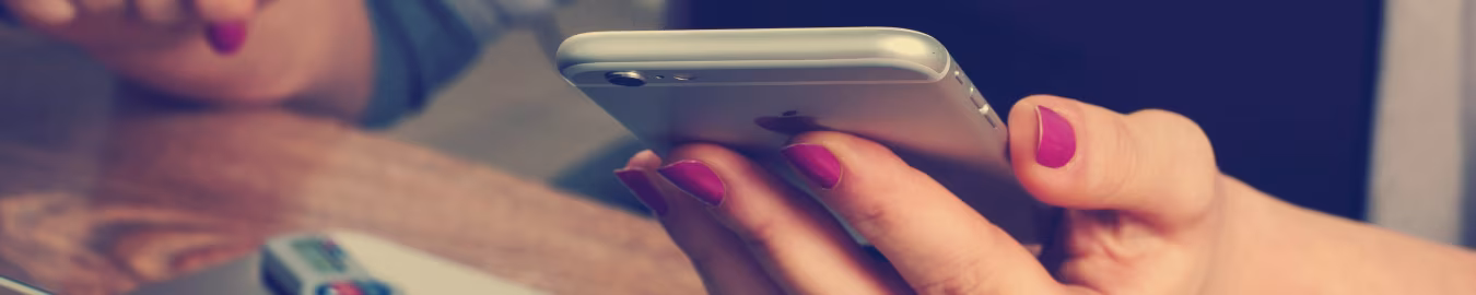 Contact close-up van hand die smartphone vasthoudt naast laptop en usb-stick op houten tafel